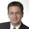 Professional headshot of a middle-aged man in a suit, friendly expression
