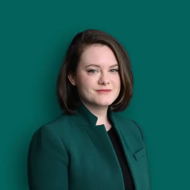 professional confident female MBA admissions consultant sitting at modern office desk, warm natural lighting, business casual attire, friendly smile, bookshelves in background, high quality portrait photography